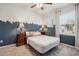 Bedroom with skyline accent wall, ceiling fan, large window, end tables with lamps, and neutral decor at 4257 Freight St, Tucker, GA 30084