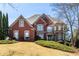 Charming two-story red brick home with a manicured lawn and mature landscaping on a sunny day at 1037 Windermere Xing, Cumming, GA 30041