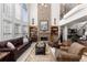 Grand living room featuring a stone fireplace, tall windows, and open staircase at 1037 Windermere Xing, Cumming, GA 30041