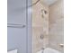 Closeup of stylish shower with beige stone tiles, silver fixtures, and bathtub edge at 195 14Th Ne St # 2402, Atlanta, GA 30309