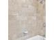 Closeup of stylish shower with beige stone tiles, silver fixtures, and bathtub edge at 195 14Th Ne St # 2402, Atlanta, GA 30309