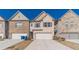 Charming townhome showcases a two-car garage and neutral brick exterior against a vibrant blue sky at 2463 Quay Rdg, Lawrenceville, GA 30044