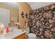 Cozy bathroom with floral shower curtain, vanity with a sink, and vintage-style sconces above the toilet at 281 Hiawassee Dr, Woodstock, GA 30188