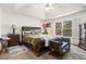 Main bedroom featuring a trey ceiling, large bed, bench, bedside tables, lamps, and windows at 625 Sycamore Glen Nw Ct, Lawrenceville, GA 30044