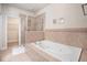 Bathroom featuring a large soaking tub, glass-enclosed shower, and tiled surround at 600 Jardin Ct # 48, Alpharetta, GA 30022