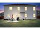 View of the backyard with patio seating, grill and gray siding of the two-story home at twilight at 7545 Rambling Vale, Cumming, GA 30028