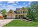 Charming two-story home featuring a manicured lawn, brick accents, a two-car garage, and traditional architectural details at 5815 P.W.A. Dr, Cumming, GA 30041