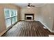 Open living room with a large window and a stone fireplace, complemented by modern wood floors at 5815 P.W.A. Dr, Cumming, GA 30041