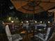 Inviting back deck at night features a dining set under an umbrella and ambient lighting throughout the backyard at 750 Maggie Nw Ct, Kennesaw, GA 30144