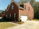 Side view of a brick home featuring an attached garage, landscaped yard, and paved driveway at 1211 Saxony Se Dr, Conyers, GA 30013