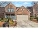 Charming brick home with a two-car garage and blue accents, enhanced by lush landscaping at 3455 Flycatcher Way, Duluth, GA 30097