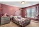 Charming bedroom with pink walls, a unique wrought-iron style bed, and bright natural light at 5136 Heron Bay Blvd, Locust Grove, GA 30248