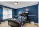 Cozy blue bedroom with a bed, toy-filled shelf, and natural light from a window at 5136 Heron Bay Blvd, Locust Grove, GA 30248