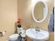 Powder room with white vanity, oval mirror, and decorative flower accents at 5136 Heron Bay Blvd, Locust Grove, GA 30248