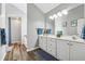 Bathroom featuring double vanity, framed mirrors, modern lighting and wood look floors at 880 Hillary Ln, Lawrenceville, GA 30043