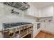 Close up of a stainless steel range with gold knobs and white cabinets in a modern kitchen at 4446 Huntington Cir, Atlanta, GA 30338