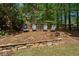 A landscaped backyard with chairs, a stone retaining wall, and mature trees offering a relaxing outdoor space at 320 N Drew Ct, Duluth, GA 30097