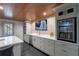 Modern basement bar area with gray cabinets, a wine cooler, a sink and light wood ceiling at 320 N Drew Ct, Duluth, GA 30097