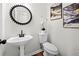 Modern powder room with pedestal sink, unique round mirror, and contemporary art at 401 Windstream Sw Dr, Marietta, GA 30060