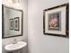 Elegant powder room featuring a pedestal sink, decorative mirror, and stylish wall art at 2910 Bishopstone Way, Cumming, GA 30040