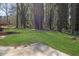 An open green backyard that features many tall trees and a small deck at 8633 Hilltop Rd, Jonesboro, GA 30236