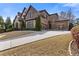 An impressive home showing the driveway leading to the three-car garage and stone and brick facade at 2814 Adams Oaks Ln, Marietta, GA 30062