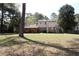 View of the back of the home with a large lawn, stone wall and trees at 3274 Jodeco Pl, Jonesboro, GA 30236
