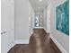 Long hallway with hardwood floors and neutral paint, featuring elegant artwork and mirrors at 3020 Barnes Mill Ct, Roswell, GA 30075