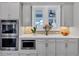 Modern kitchen with double ovens, white countertops, light gray cabinets and a designer tile backsplash at 3020 Barnes Mill Ct, Roswell, GA 30075