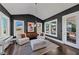 Bright sunroom with comfortable seating, dark accent walls, modern chandelier, and view of outdoor play area at 3020 Barnes Mill Ct, Roswell, GA 30075