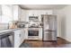 Modern kitchen features stainless steel appliances, white cabinets, granite countertops, and hardwood floors at 1893 Windsor Sw Dr, Atlanta, GA 30311