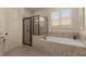 Bright bathroom features a black framed glass shower and separate tub beneath a window, tiled with neutral tones at 2564 Lulworth Ne Ln, Marietta, GA 30062