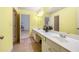 Bright yellow bathroom with double sinks, mirror, and adjacent room, offers style and functionality at 1415 Swiftwater Cir, Mcdonough, GA 30252