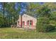 Charming home featuring red shutters, a brick base, and a cozy front porch, surrounded by lush greenery and mature trees at 5520 Glore Sw Dr, Mableton, GA 30126