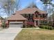 Charming brick home featuring a two-car garage, manicured lawn, mature trees, and attractive landscaping at 960 Whitehawk Trl, Lawrenceville, GA 30043