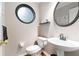 Half bathroom with an oval decorative window, round mirror, pedestal sink, and tiled floors at 3993 Amberley Ln, Marietta, GA 30062