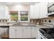 White kitchen featuring stainless appliances, granite countertops, hardwood floors, and tile backsplash at 3993 Amberley Ln, Marietta, GA 30062