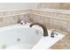 Close-up of a jetted tub featuring decorative tile and bronze fixtures at 3993 Amberley Ln, Marietta, GA 30062