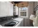 Cozy laundry room with checkered wallpaper, storage cabinets, and modern washer and dryer at 1354 Larson Sw Ct, Marietta, GA 30064