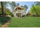 The backyard features a multi-tiered deck and lush green lawn surrounded by mature trees and landscaping at 2687 Ashford Ne Rd, Brookhaven, GA 30319