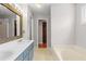 Bathroom with double sink vanity, wooden framed mirror, tub and walk-in closet access at 2840 Ivy Mill Dr, Buford, GA 30519