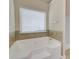 Corner bathtub illuminated by a window, accented with tile surround and chrome fixtures at 2205 Capella Sw Cir, Atlanta, GA 30331