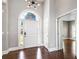 Light-filled foyer with stylish chandelier, arched doorway, white door, and hardwood floors, creating an inviting entrance at 525 James Lee Dr, Suwanee, GA 30024
