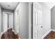 Hallway with neutral walls, hardwood floors, and white doors leading to rooms and a bathroom at 525 James Lee Dr, Suwanee, GA 30024