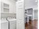 Laundry area featuring washer and dryer with overhead shelving; access to a modern kitchen space at 525 James Lee Dr, Suwanee, GA 30024