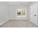 Neutral bedroom with plush carpet, window view, and white door to hall at 25 Fourwood Dr, Covington, GA 30016