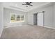 Spacious main bedroom with a ceiling fan, a sliding barn door, large windows, and plush carpet at 25 Fourwood Dr, Covington, GA 30016