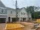 New townhome exteriors in gray and white brick with driveways, landscaping, and construction bins at 125 Priestwood Ln, Acworth, GA 30102