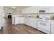 Bright kitchen with white cabinets, appliances, and wood-look flooring with adjoining Gathering room at 3182 Mill Springs Cir, Buford, GA 30519