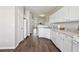 Open-concept kitchen with white cabinets, appliances, and wood-look flooring throughout the main level at 3182 Mill Springs Cir, Buford, GA 30519